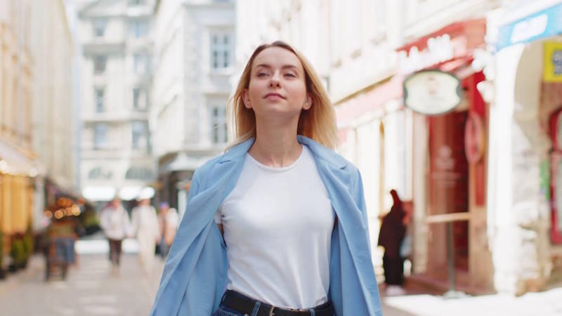 Jeune femme marchant en ville, le visage apaisé et confiant, symbole d’une reconstruction après une rupture amoureuse.