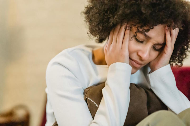 Femme pensive tenant sa tête entre ses mains, image de douleur et de confusion après une rupture amoureuse.