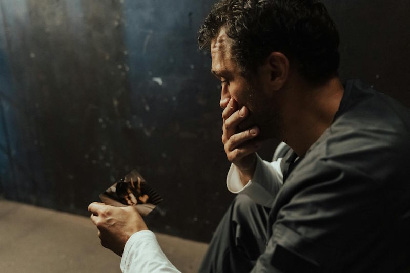 Un homme pensif regarde une photo de son ex, partagé entre regret et désir de reconquête après la rupture.