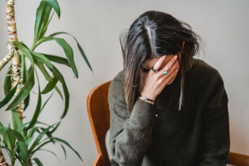 Femme assise la tête dans la main, épuisée après des disputes de couple répétitives